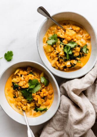 two bowls of coconut cauliflower curry topped with cilantro