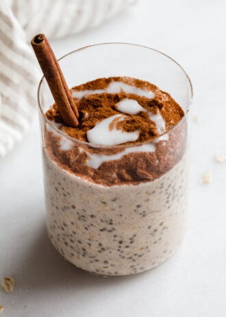 a cup of cinnamon roll overnight oats with a cinnamon stick in it
