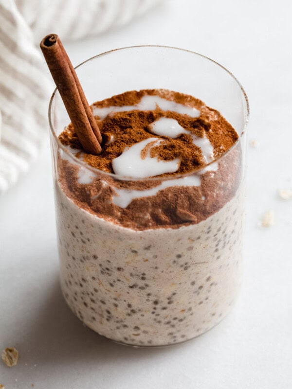 a cup of cinnamon roll overnight oats with a cinnamon stick in it
