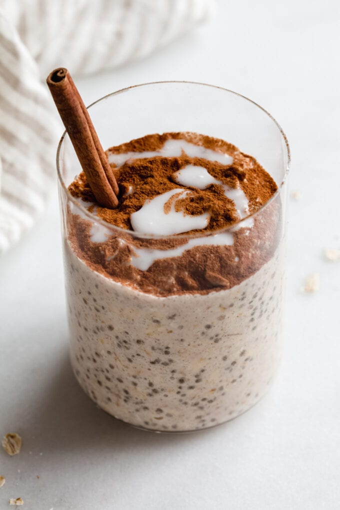 a cup of cinnamon roll overnight oats with a cinnamon stick in it