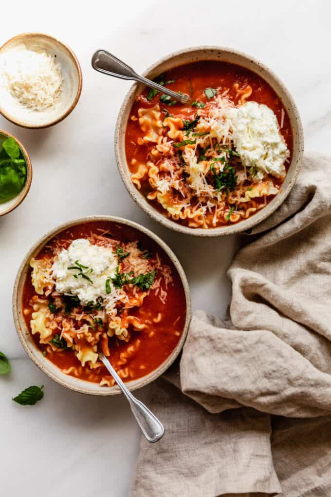 two bowls of vegetarian lasagna soup with a napkin on the side