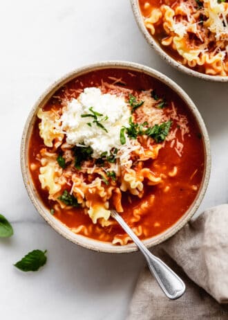 lasagna soup in a bowl topped with ricotta and basil