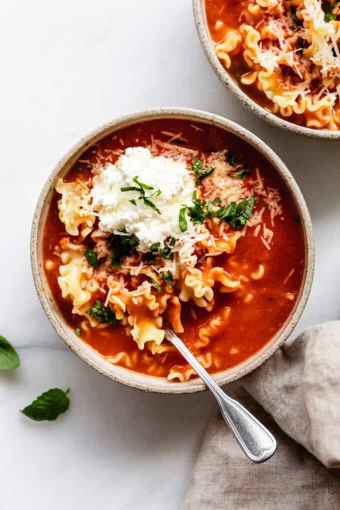 lasagna soup in a bowl topped with ricotta and basil
