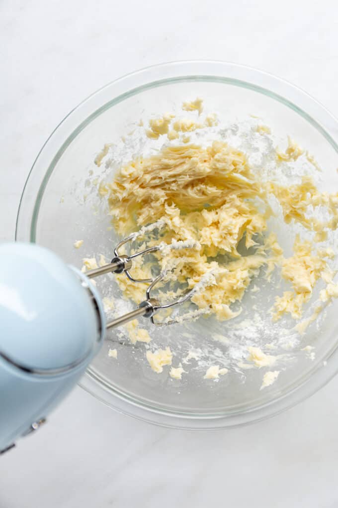 a hand held mixer mixing butter and sugar together