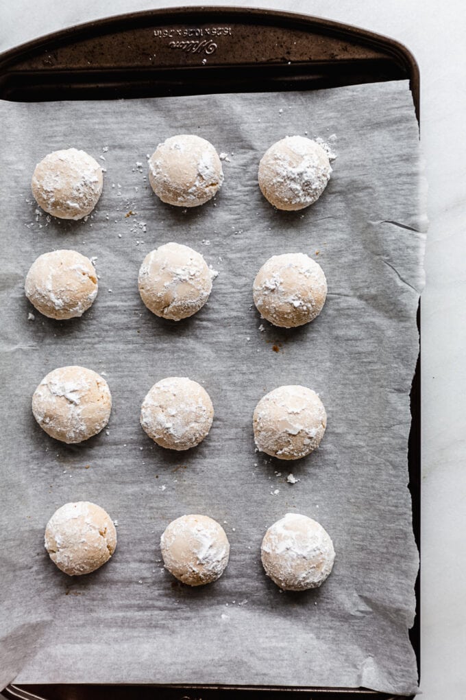 almond snowball cookies dipped in powdered sugar on a baking sheet