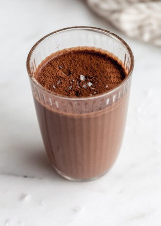 chocolate banana smoothie in a glass topped with cocoa powder