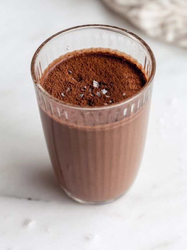 chocolate banana smoothie in a glass topped with cocoa powder