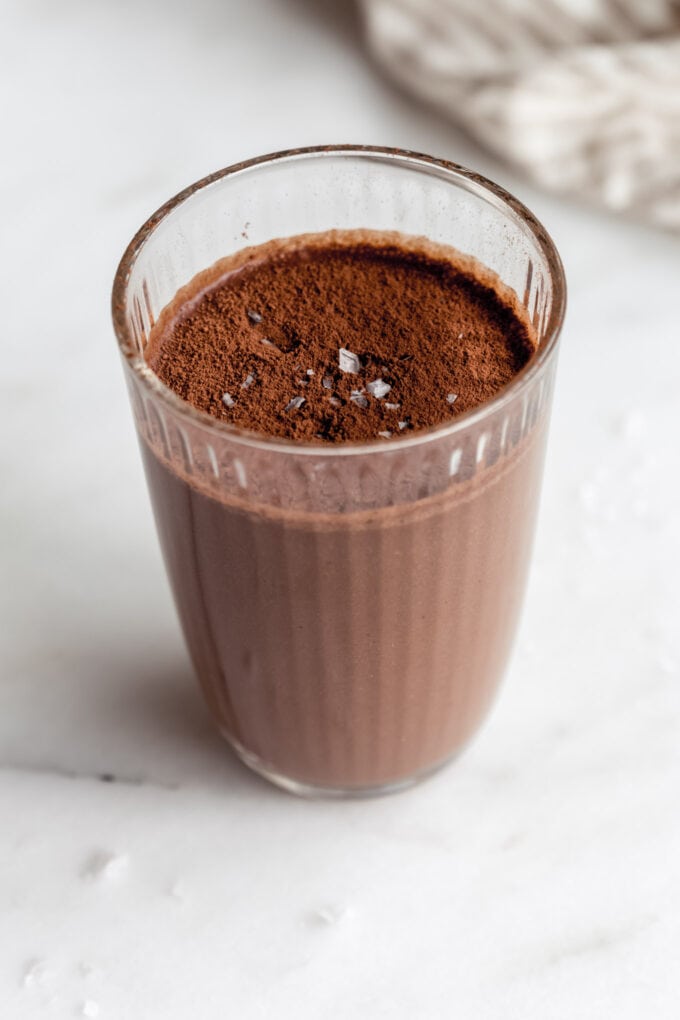 chocolate banana smoothie in a glass topped with cocoa powder