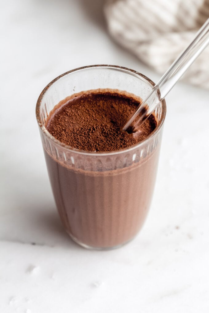 a glass of chocolate banana smoothie with a glass straw