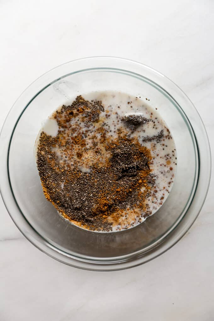 chia seeds, coconut milk and spices in a clear mixing bowl