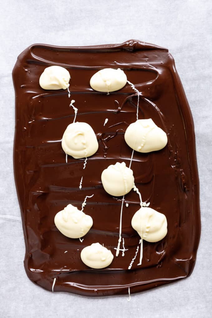 dark chocolate with dollops of white chocolate spread onto parchment paper