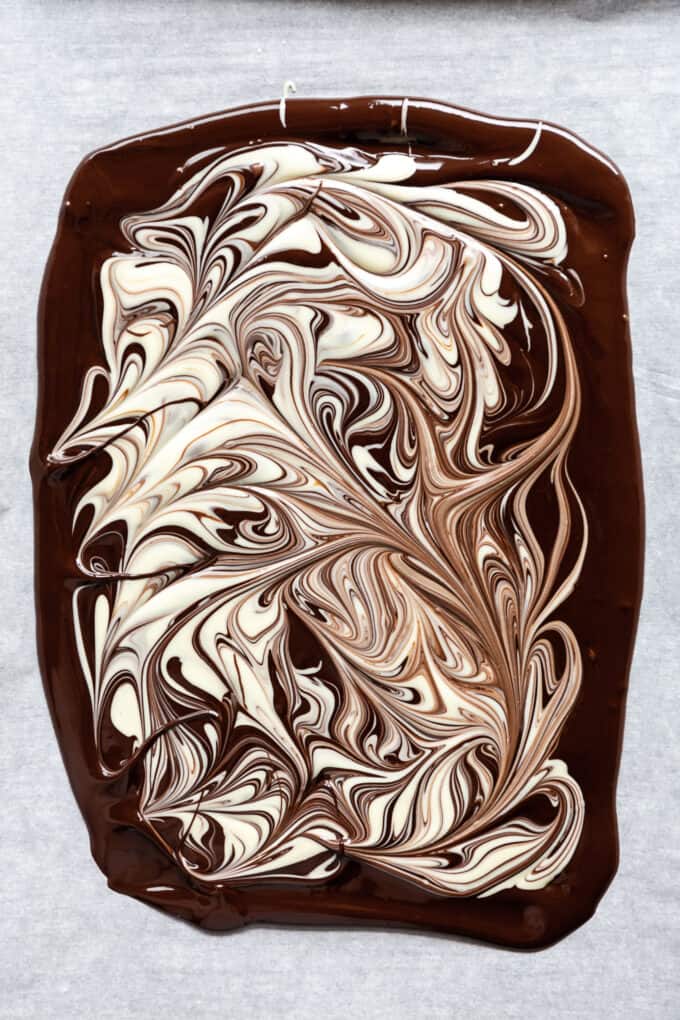 dark chocolate melted on a baking sheet with white chocolate swirls on it