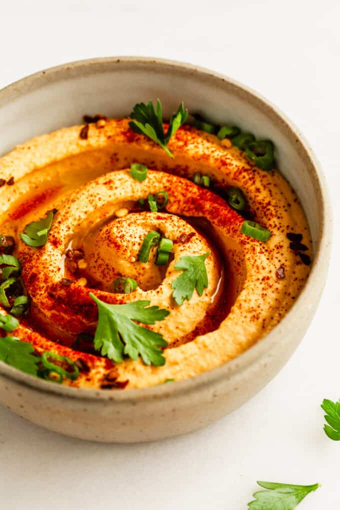 buffalo hummus in a bowl topped with paprika, green onion and parsley