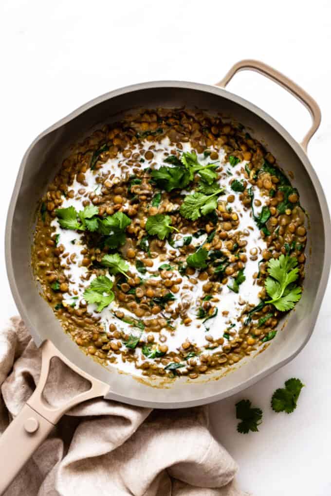 Thai green curry lentils in a large pan topped with coconut milk and cilantro