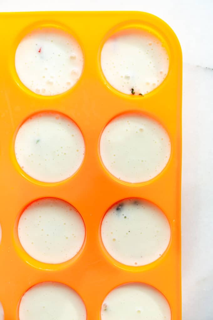 unbaked egg white bites in an orange muffin pan