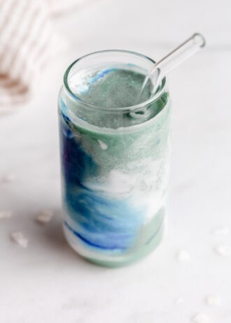 blue spirulina smoothie in a glass with a straw
