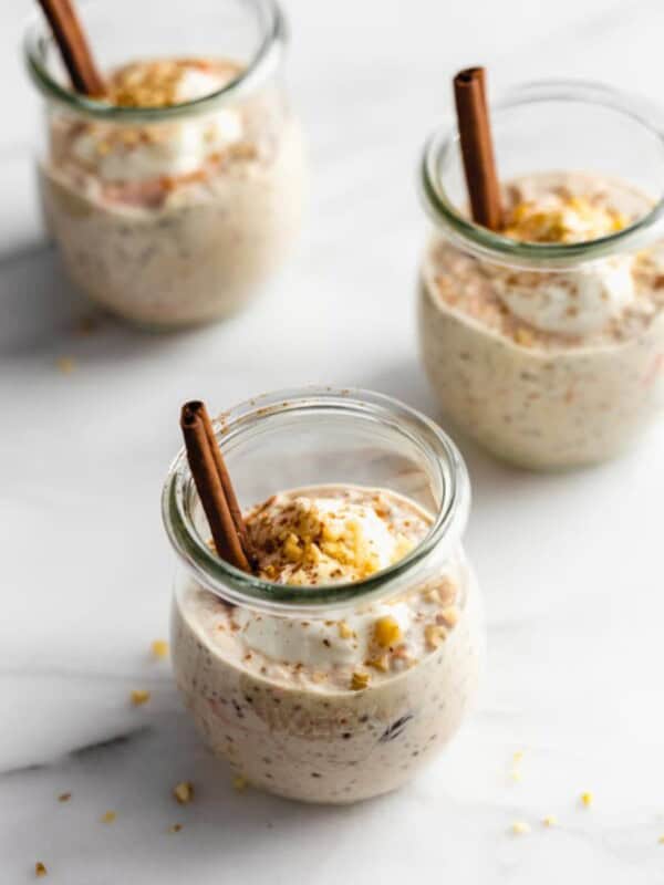 carrot cake overnight oats in 3 jars topped with yogurt and walnuts