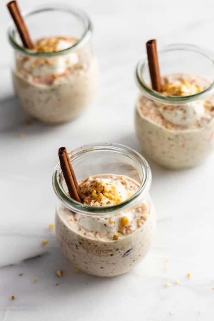 carrot cake overnight oats in 3 jars topped with yogurt and walnuts