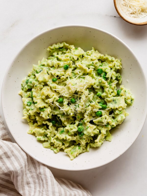 ricotta and pea pasta in a bowl with a striped napkin on the side