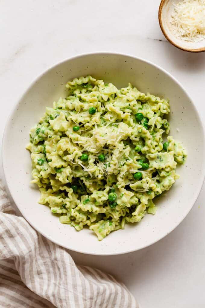 ricotta and pea pasta in a bowl with a striped napkin on the side