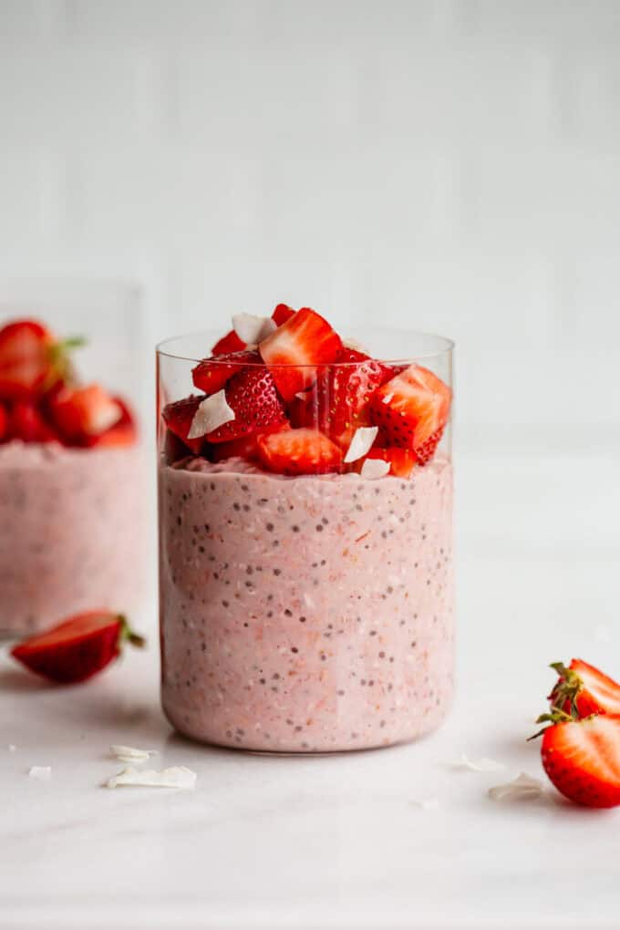 a jar of strawberry overnight oats with strawberries and some cut strawberries on the side