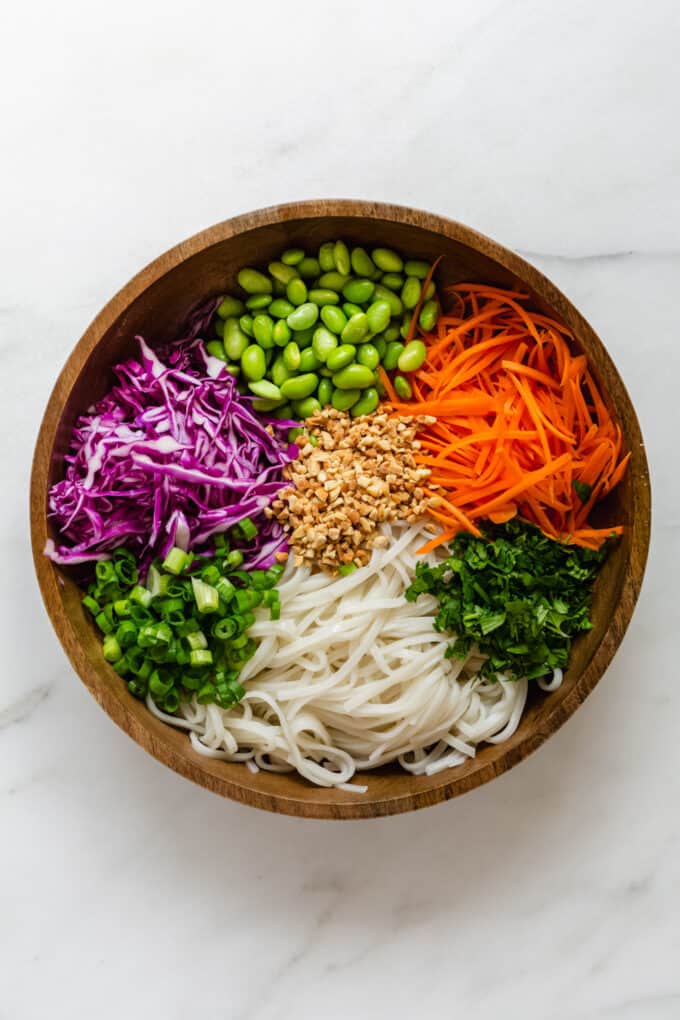 Noodles, vegetables and crushed peanuts in a wood bowl