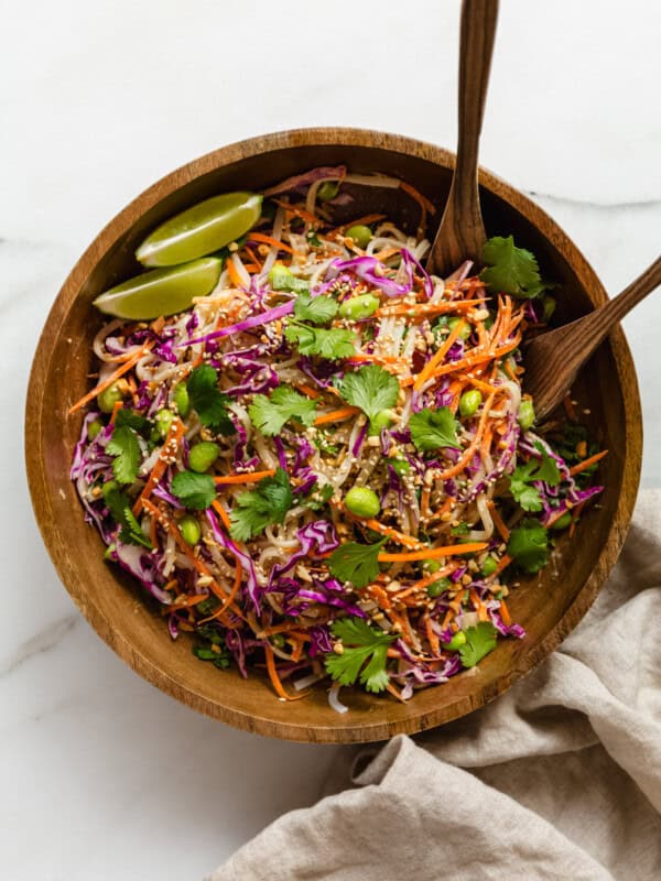 a wooden bowl with wooden spoons with a Thai noodle salad in it