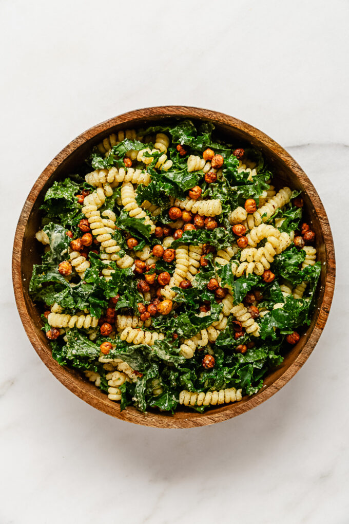 pasta salad with kale and roasted chickpeas in a wooden bowl