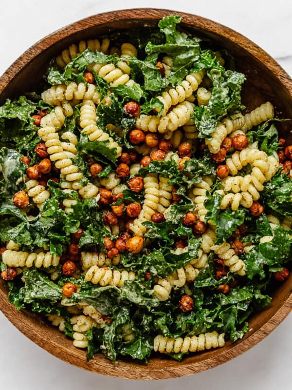 a kale caesar pasta salad in a wood mixing bowl