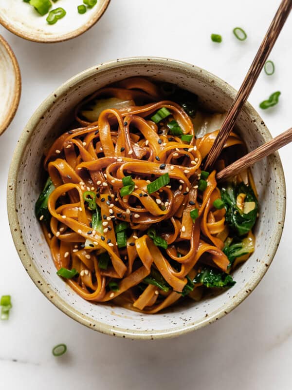 miso noodles in a white speckled bowl with wood chopsticks