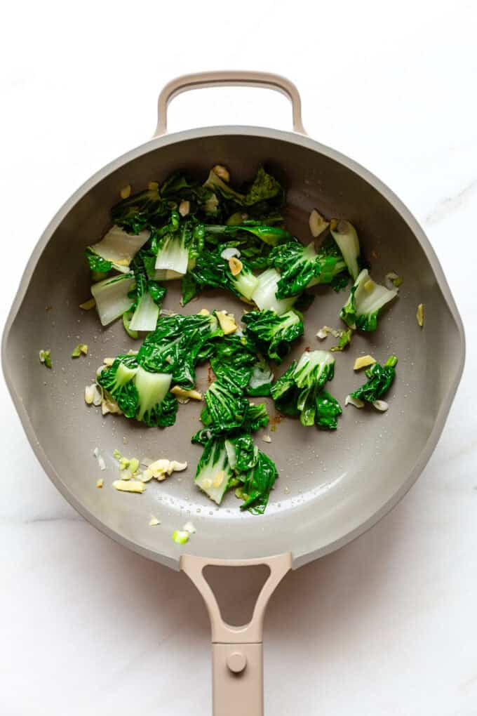 stir-fried bok choy in a taupe pan
