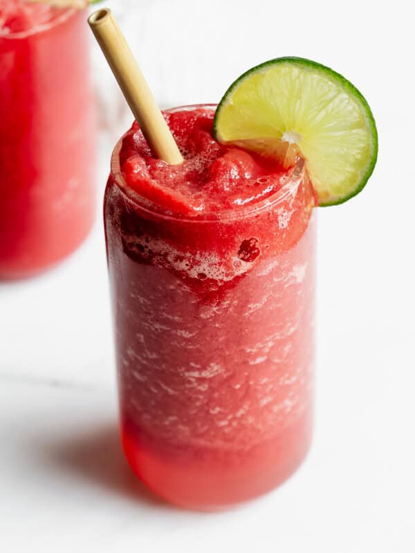 a watermelon slushie with a lime slice and bamboo straw
