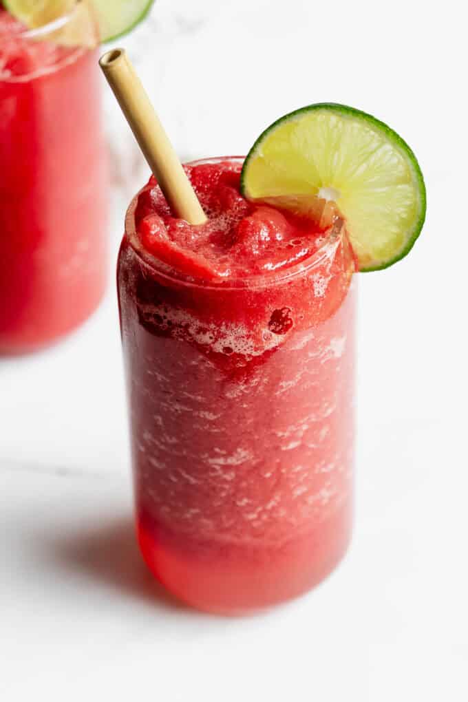 a watermelon slushie with a lime slice and bamboo straw