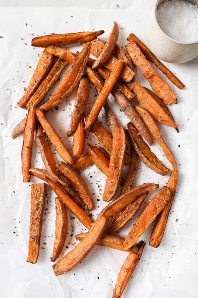 Sweet potato wedges on white parchment paper with a side of salt