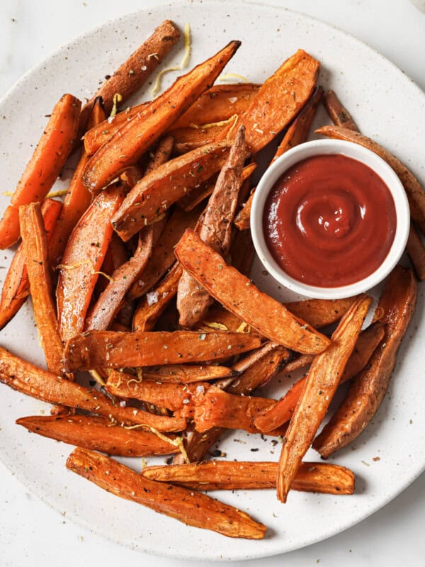 sweet potato wedges on a white plate with a side of ketchup