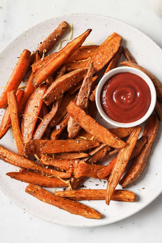 sweet potato wedges on a white plate with a side of ketchup