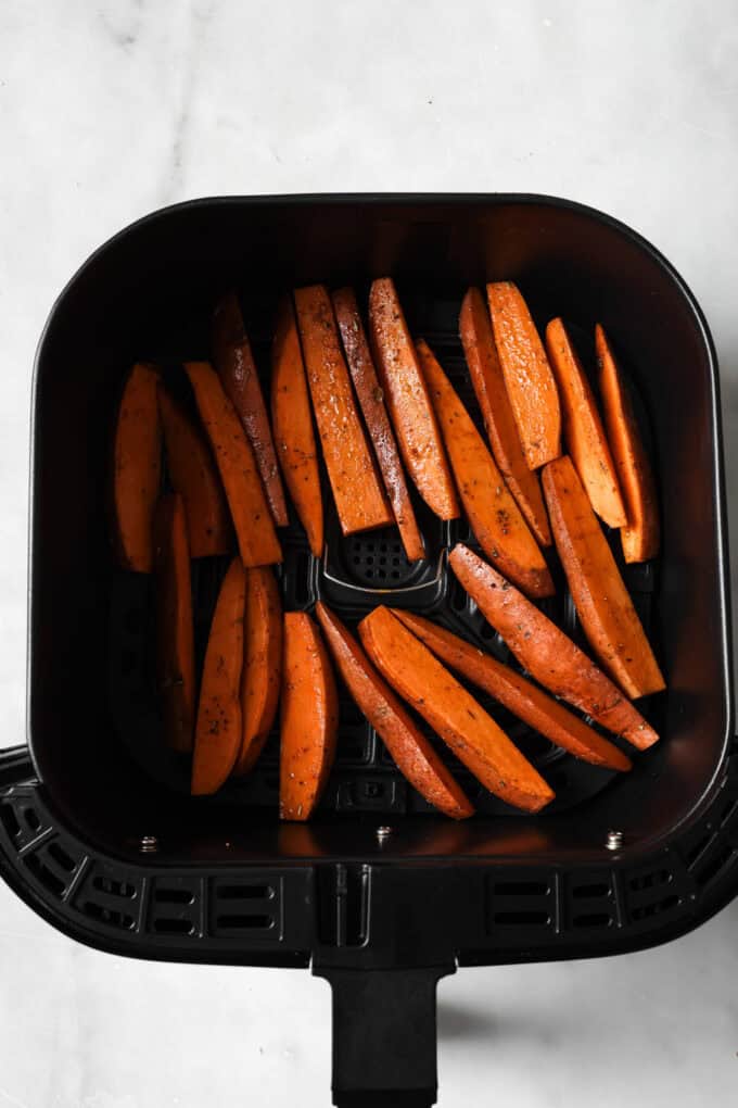 uncooked sweet potato wedges in an air fryer