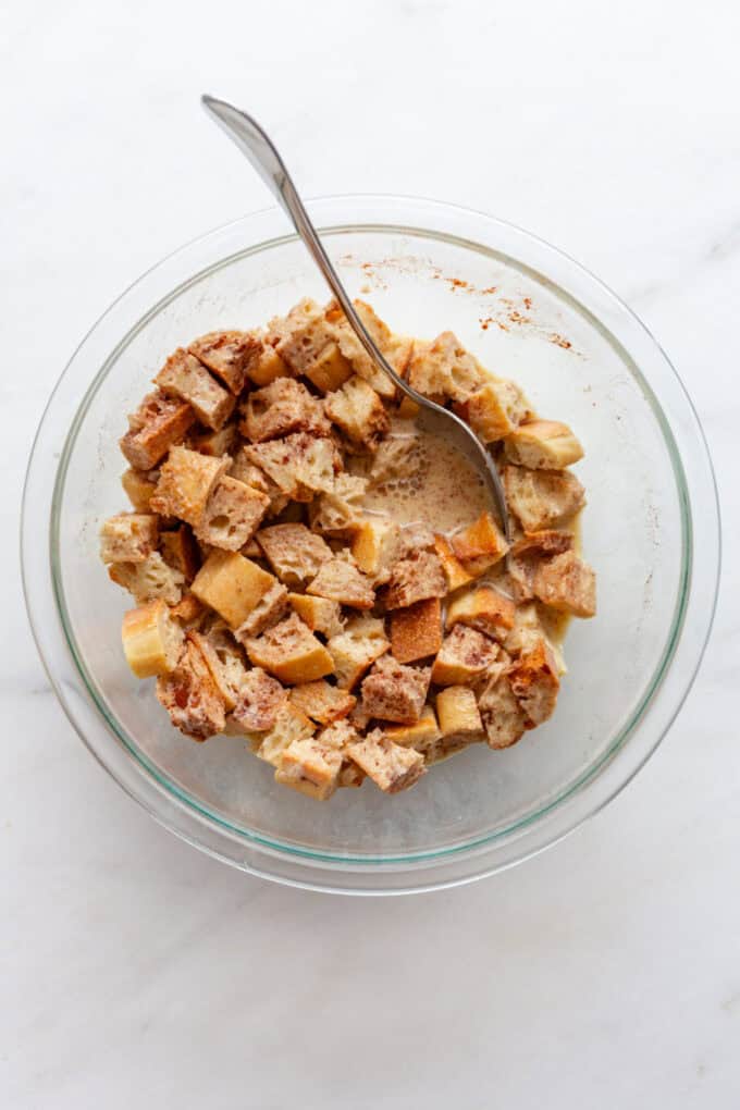 bread mixed with eggs, milk, cinnamon and vanilla in a mixing bowl