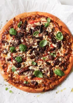 mediterranean pizza topped with fresh basil leaves