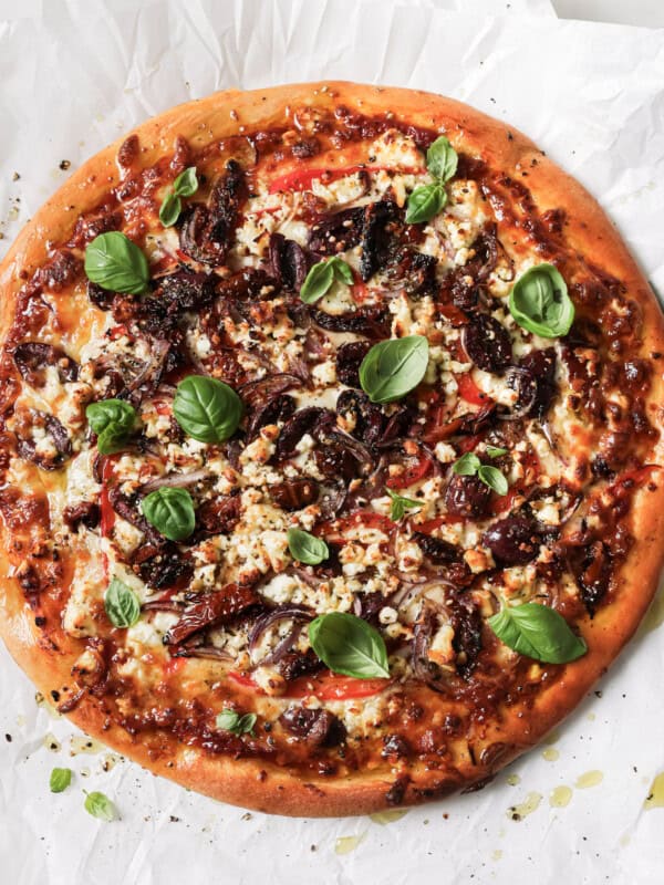 mediterranean pizza topped with fresh basil leaves
