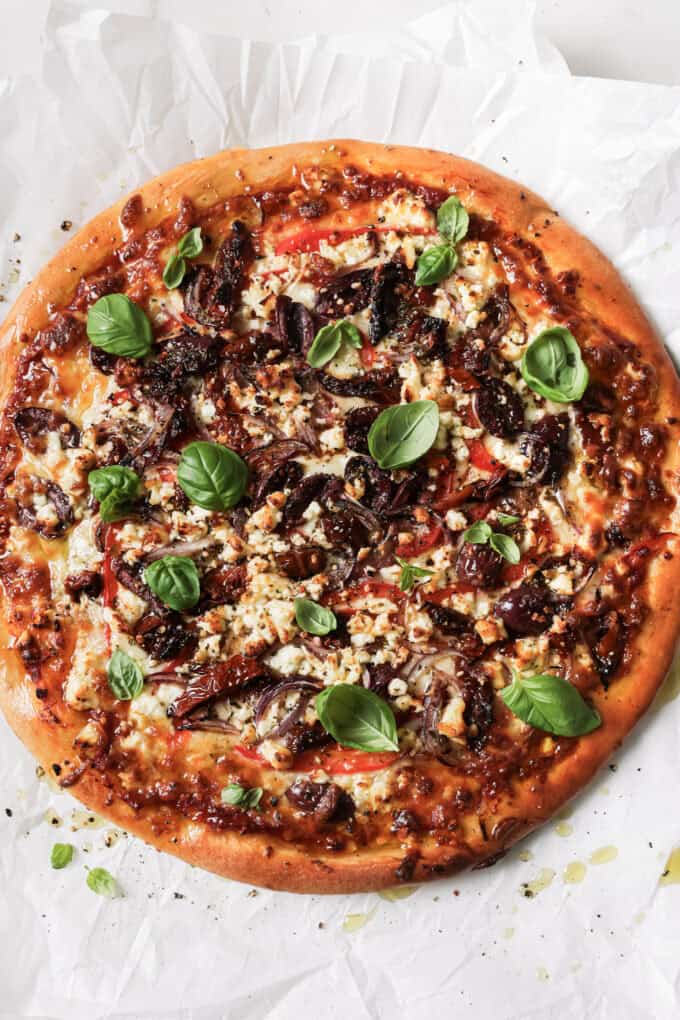 mediterranean pizza topped with fresh basil leaves