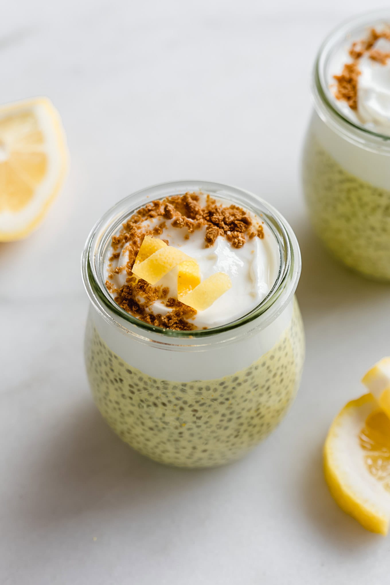 A cup of lemon chia pudding topped with yogurt, graham cracker crumbs, and a lemon twist.