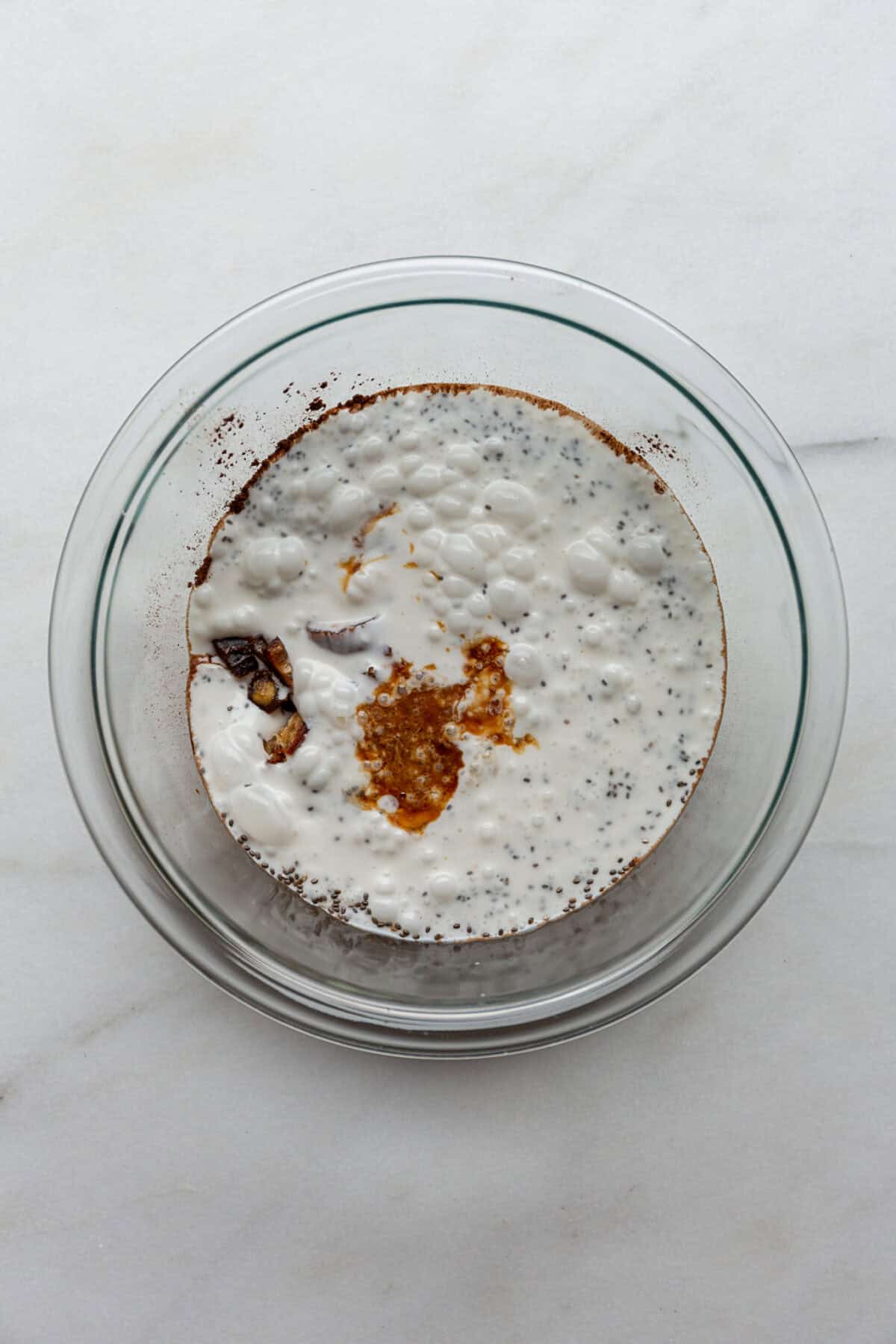 coconut milk, vanilla, chia seeds, dates and cocoa powder in a clear mixing bowl.