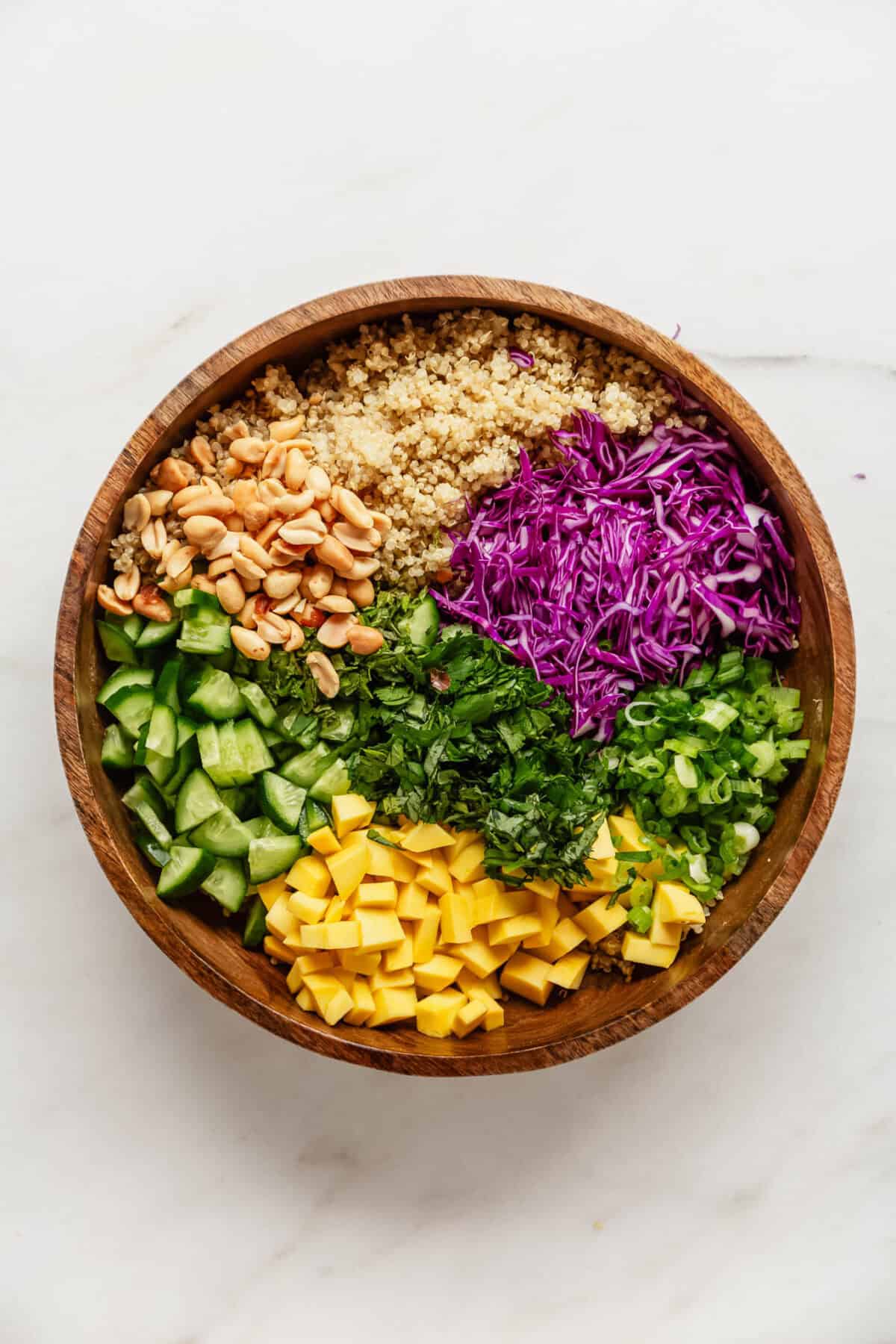 Ingredients for a Thai quinoa salad in a wood salad bowl.