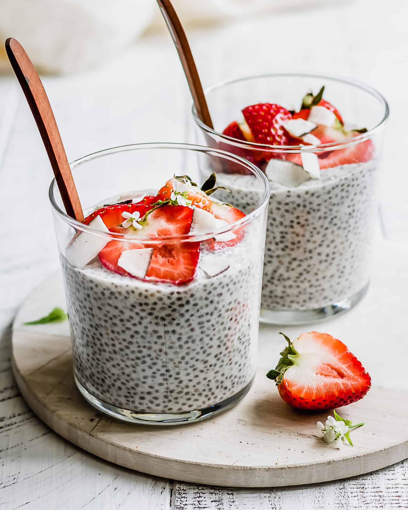 two cups of coconut chia pudding topped with strawberries.