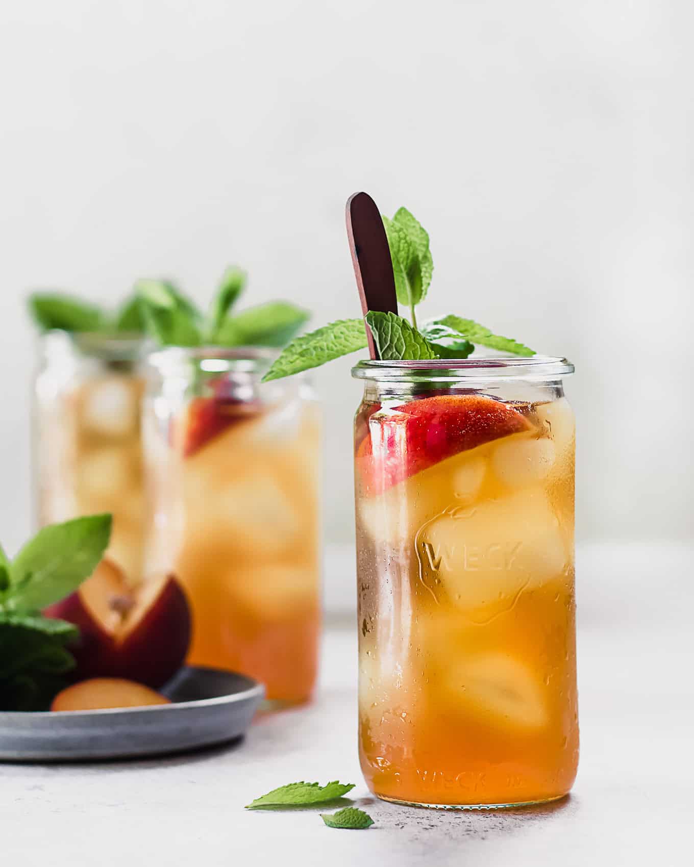 A cup of cold brew peach iced tea with peaches and mint.