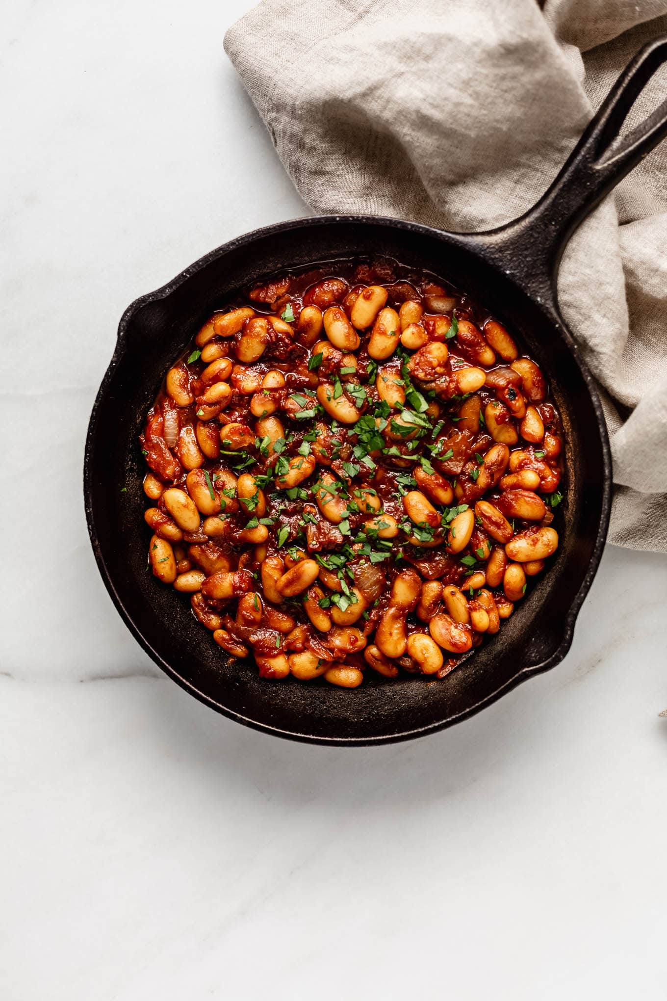 Maple baked beans in a cast iron skillet.