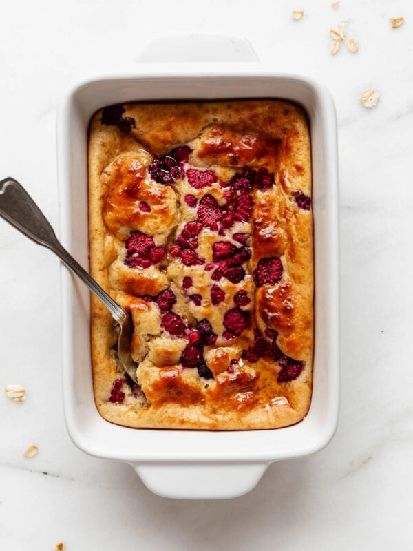 a pancake bowl with raspberries in a white baking dish.