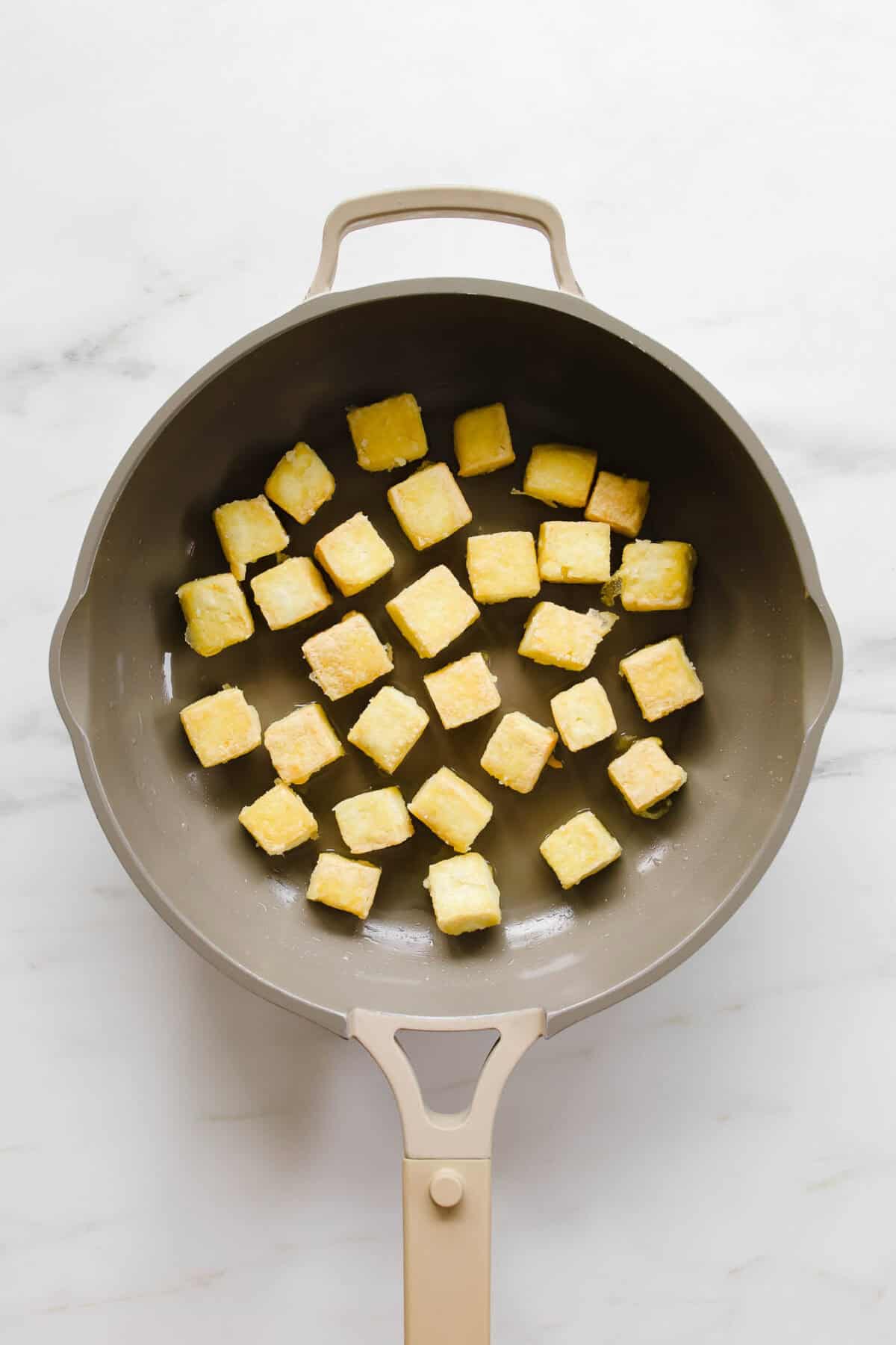 Crispy cubes of tofu in a pan.
