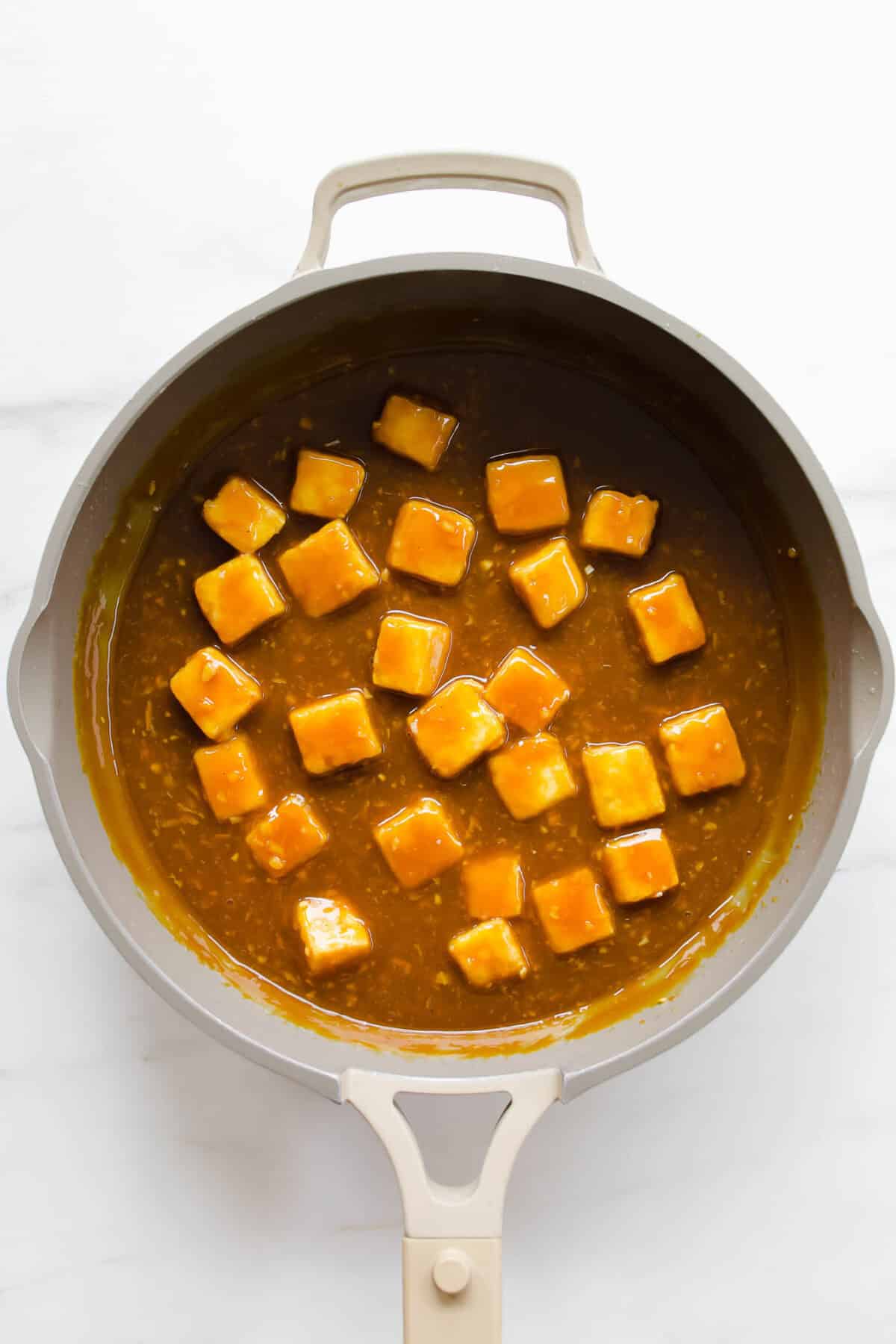 Orange tofu in a pan.